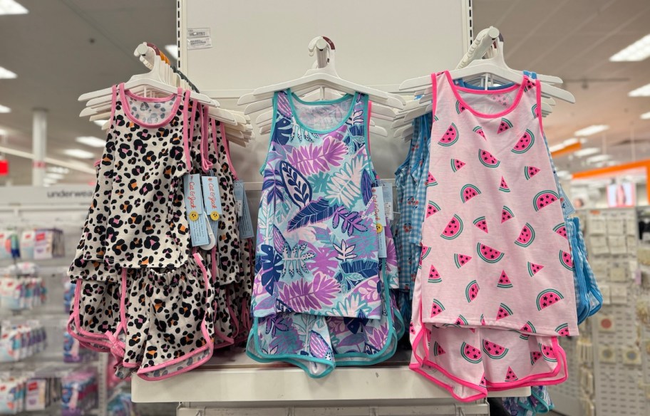 three sets of different patterned girls pajamas hanging on target store shelves