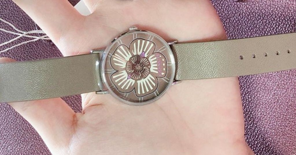 flower coach watch on hand with shiny purple background