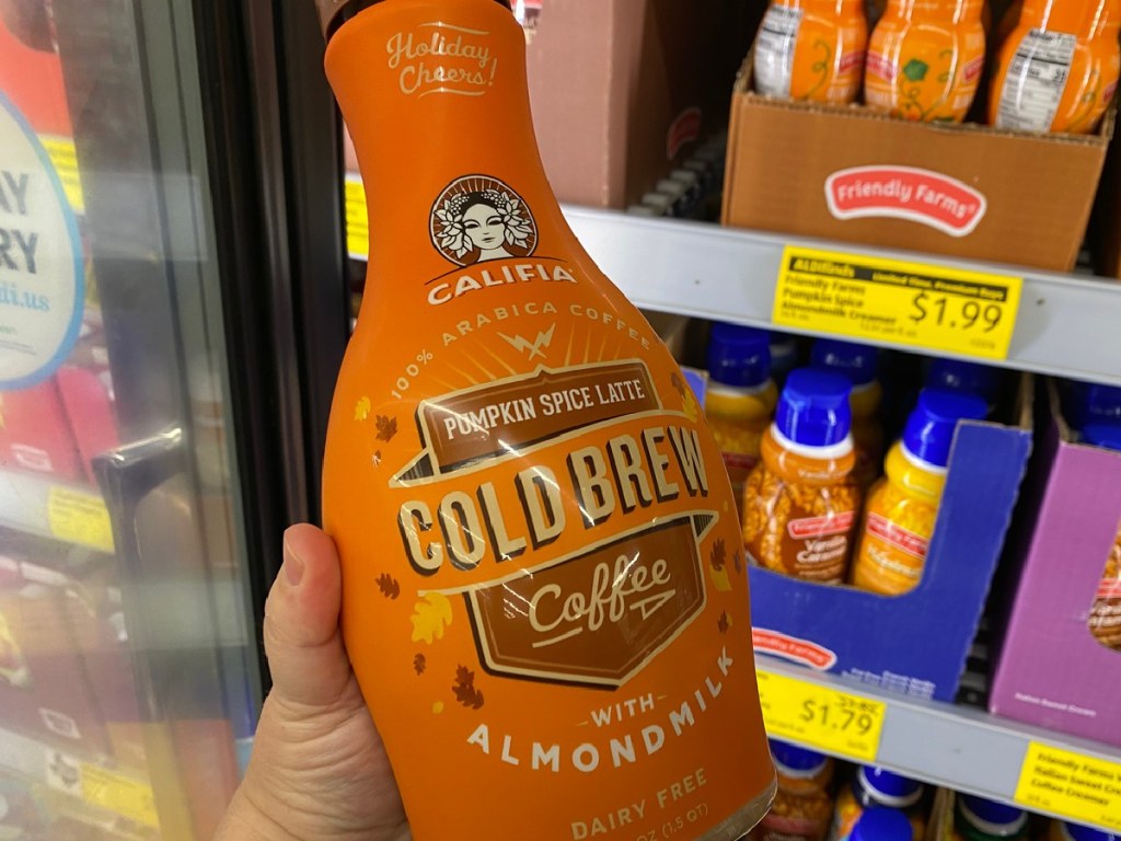 hand holding big bottle of cold brew coffee by store refrigerator