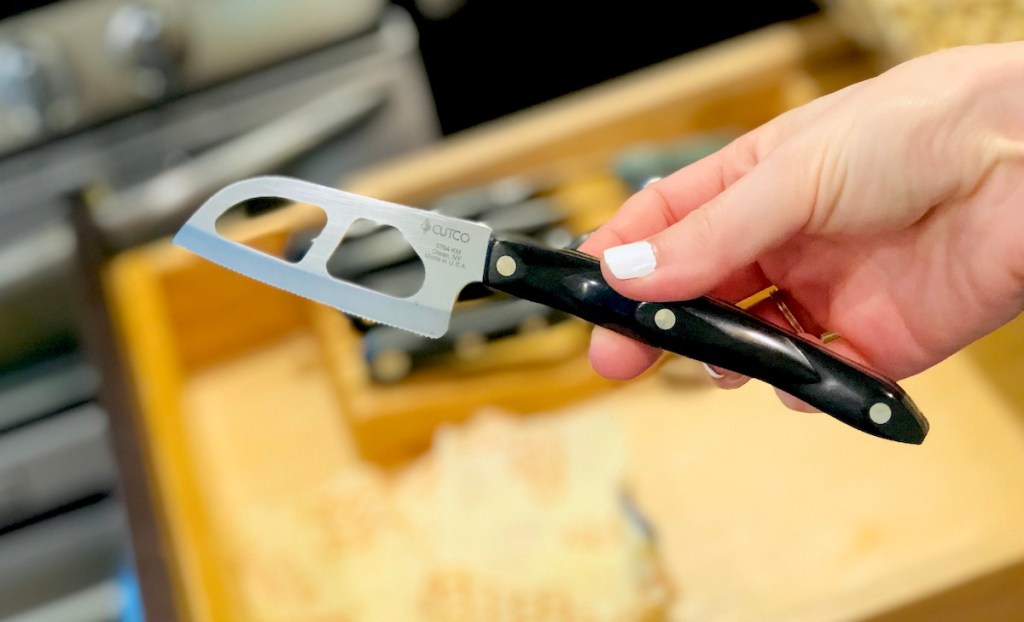 hand holding a cutco knife in front of open kitchen drawer