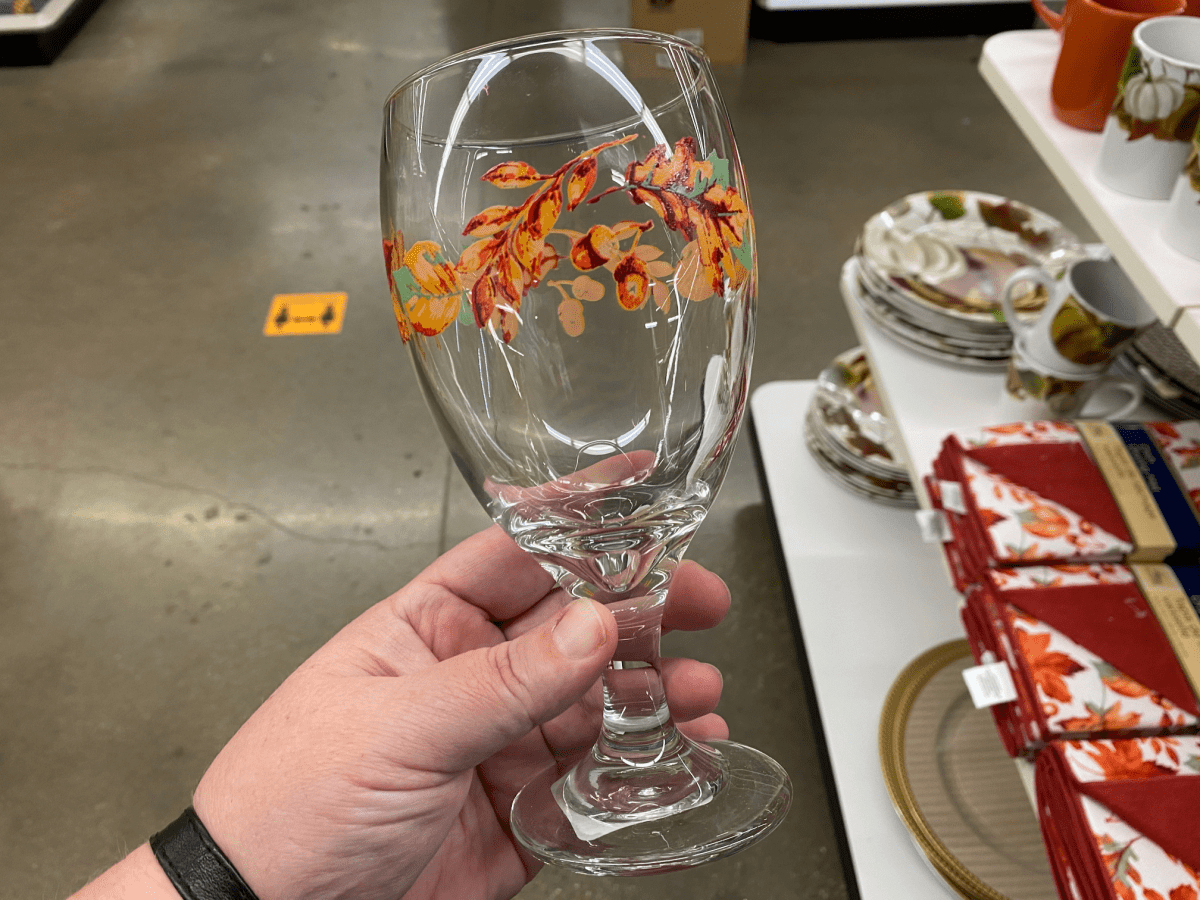 hand holding glass with fall leaves painted on it