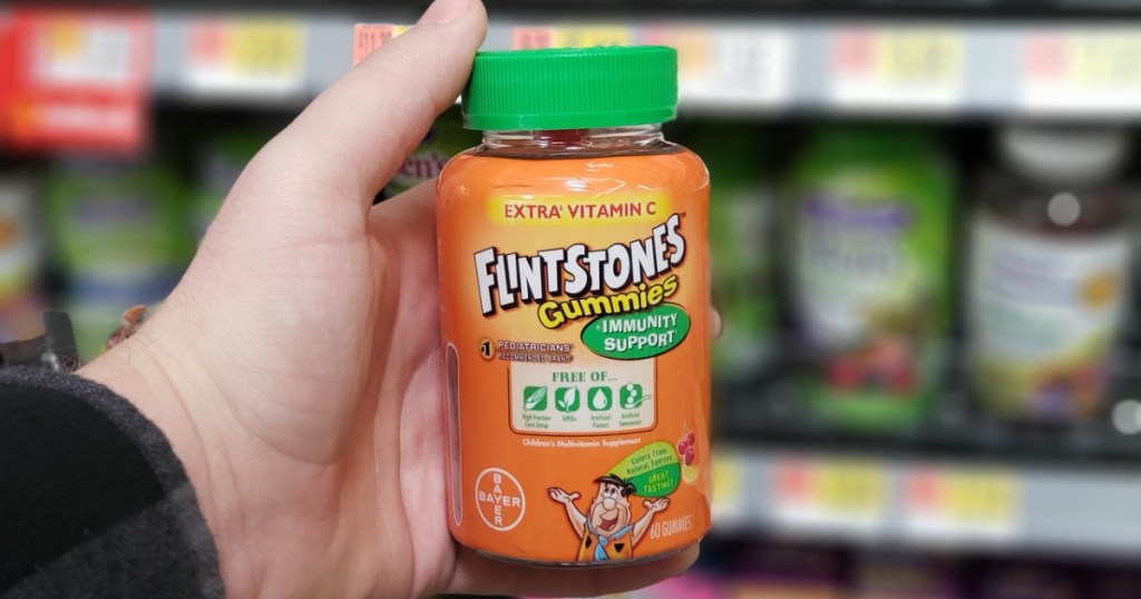 hand holding bottle of kids vitamins in front of store display