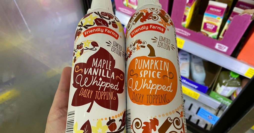 hand holding two cans of fall flavored whipped topping