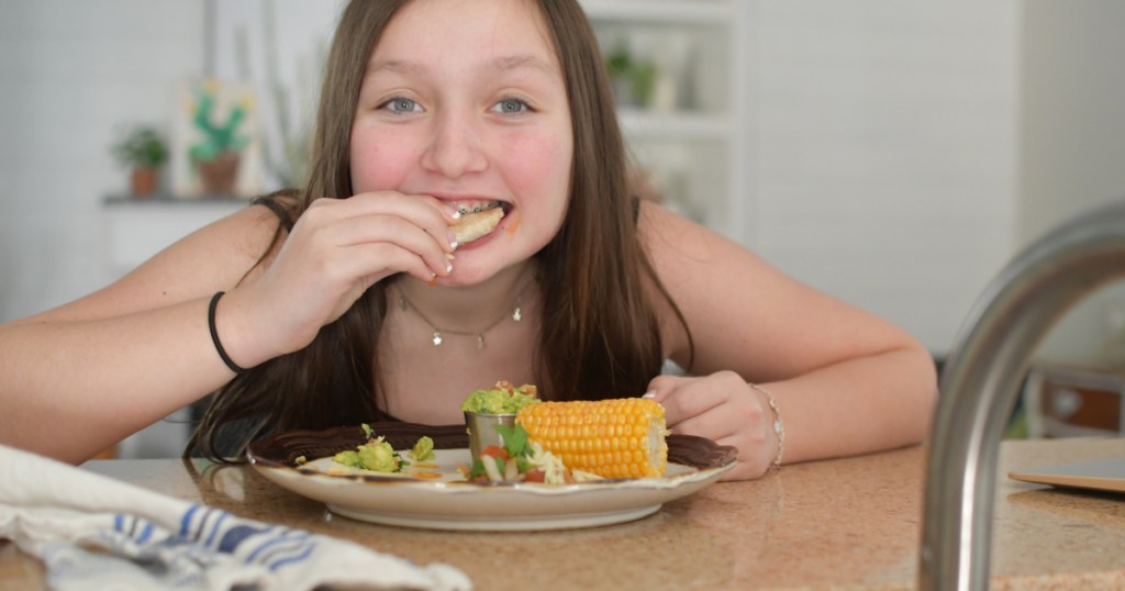 girl eating tacos on a plate