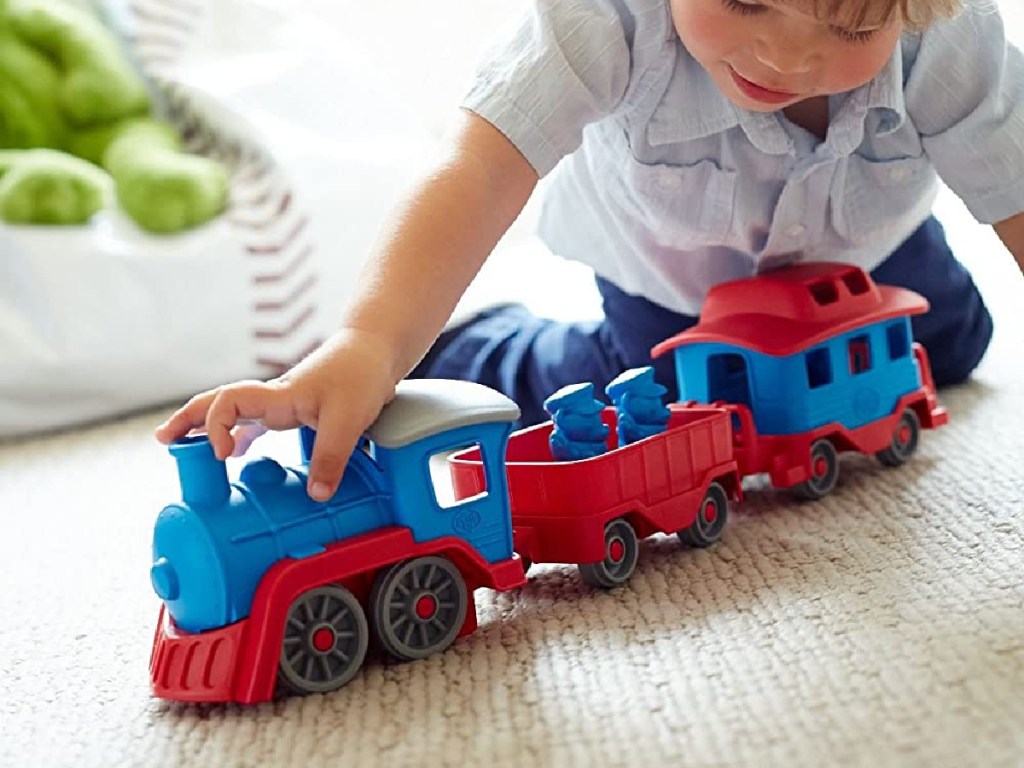 little boy playing with toy train on floor