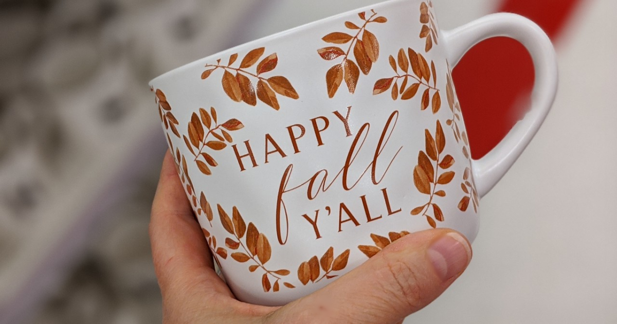 hand holding mug with fall leaves and words on it
