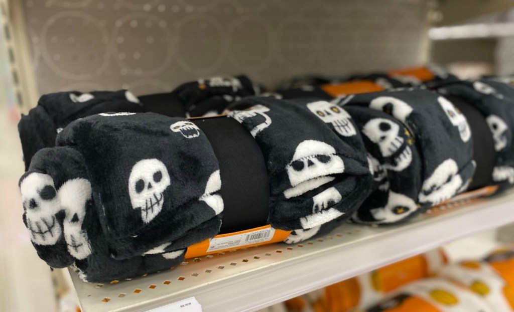 black throw blanket with white skulls on a store shelf