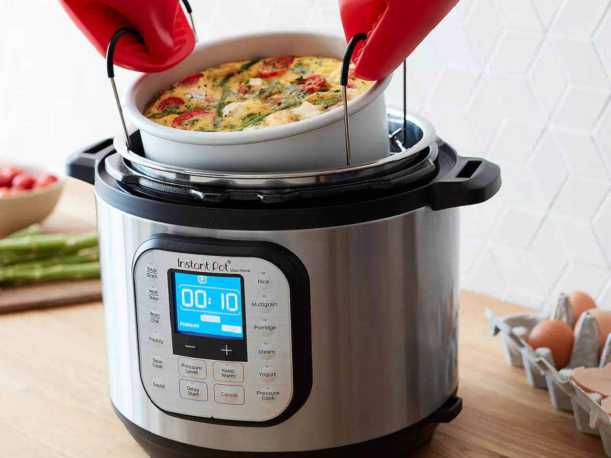 hands wearing oven mitts taking bowl out of Instant Pot