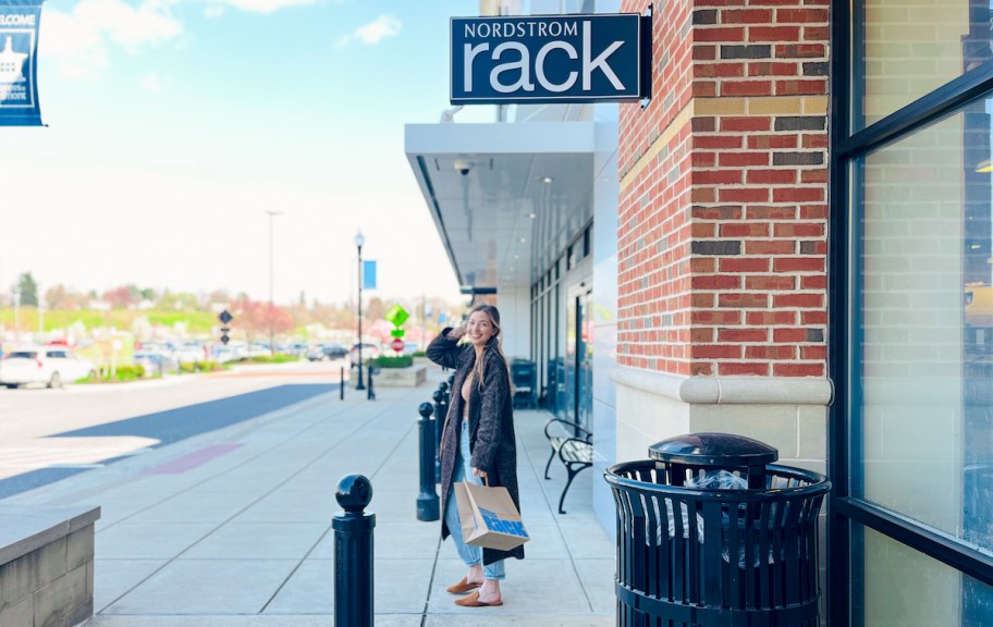 woman with shopping bag standing outside of nordstrom rack