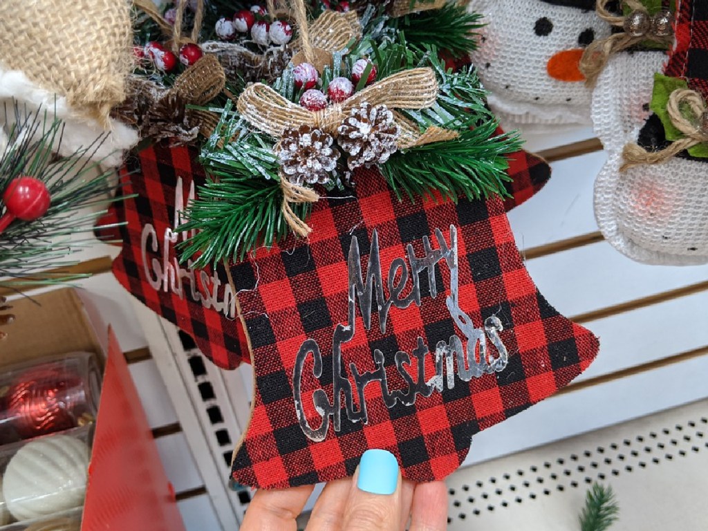 hand holding plaid bell shaped Christmas ornament by store display