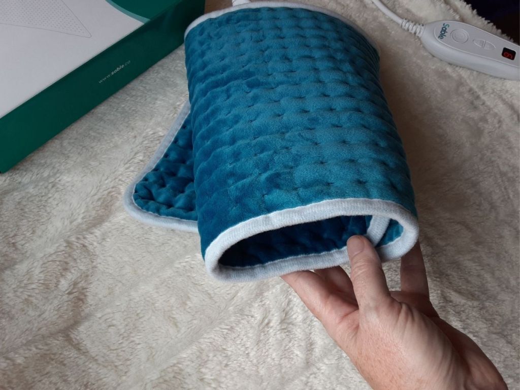 hand touching rolled up blue heating pad