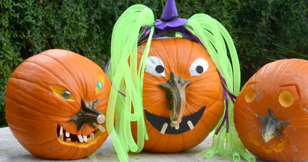 three pumpkins decorated with stems on nose and green hair