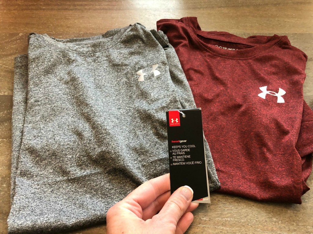 under armour boys tees on table with hand showing tag
