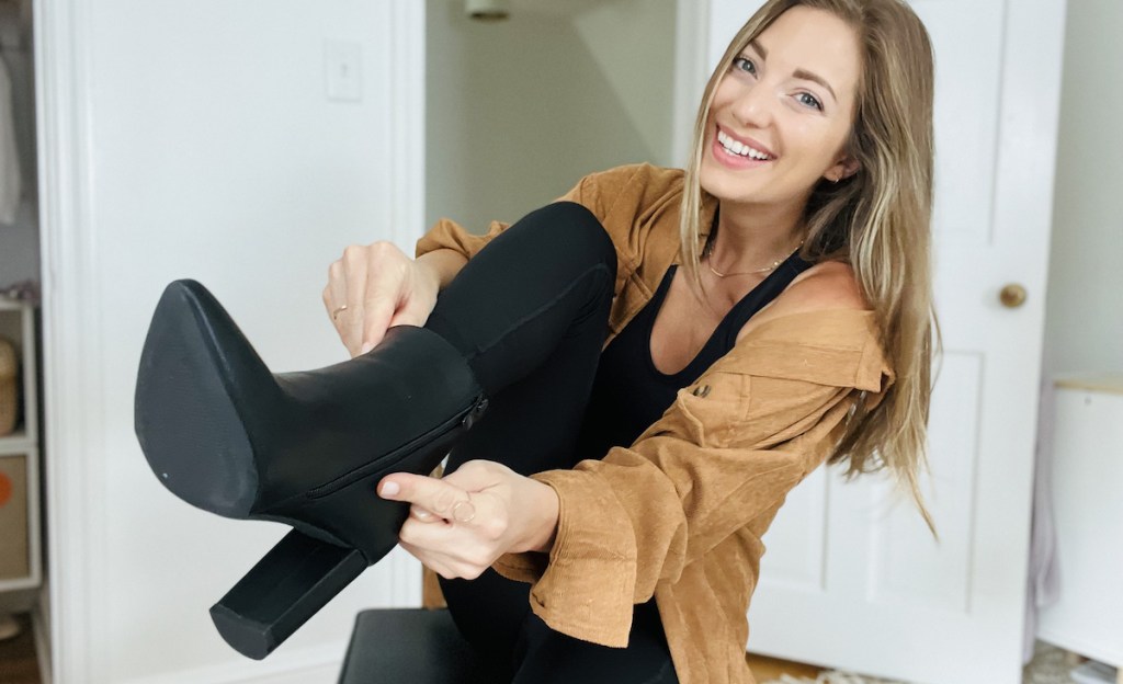 woman smiling pulling on black booties
