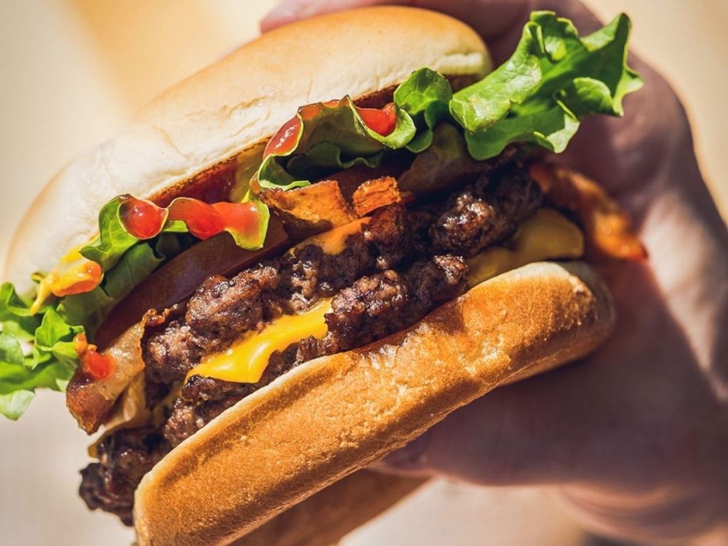 hand holding double cheeseburger