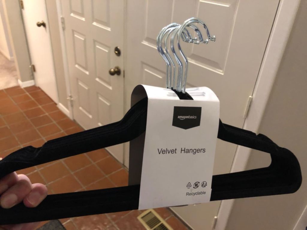 hand holding a pack of Amazon Basics hangers