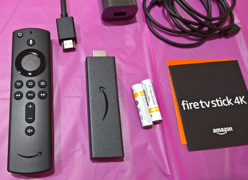 amazon fire tv stick, remote, cable, and guide laid out on table with purple tablecloth