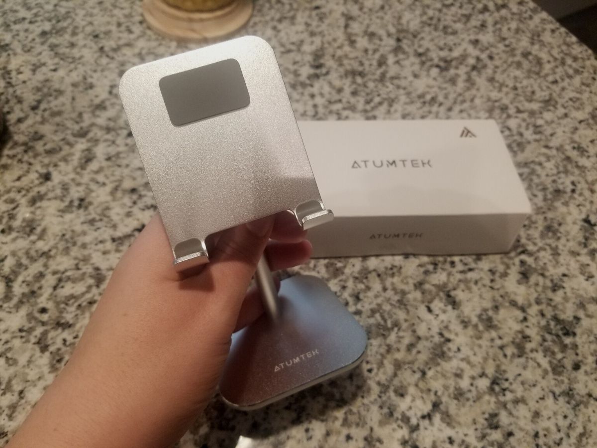 hand holding Atumtek phone stand with box in background