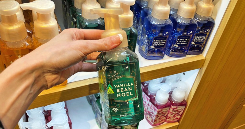 woman holding up green bottle of bath & body works hand soap in vanilla bean noel scent