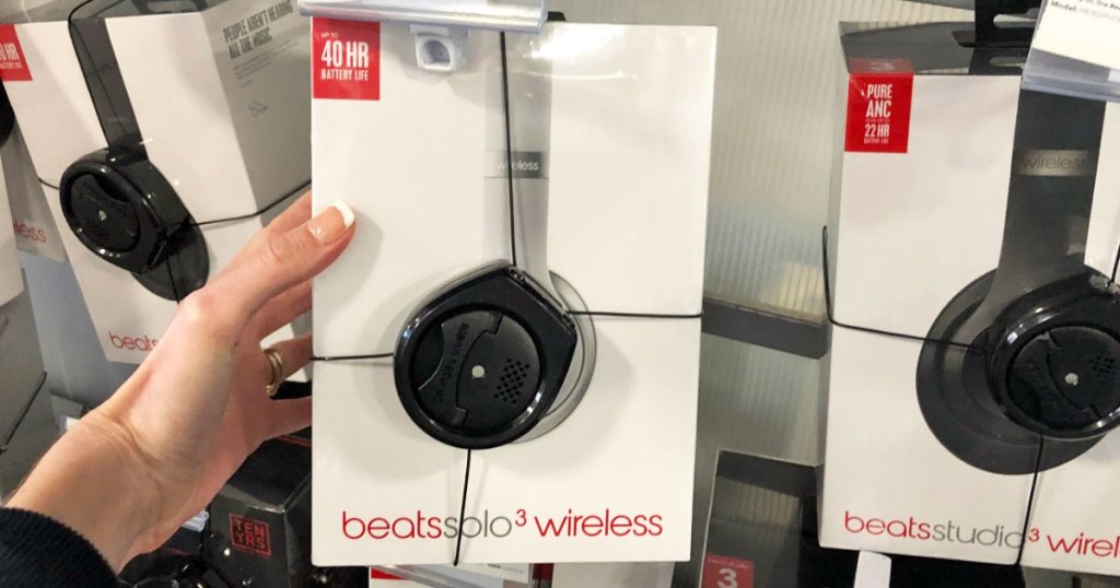 person holding a box for silver beats solo 3 headphones on store display