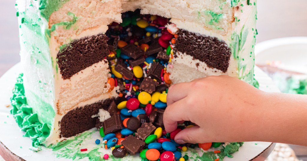 boy grabbing candy from inside of cake