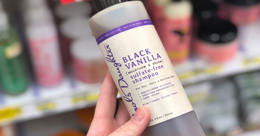 person holding up a bottle of carol's daughter black vanilla shampoo