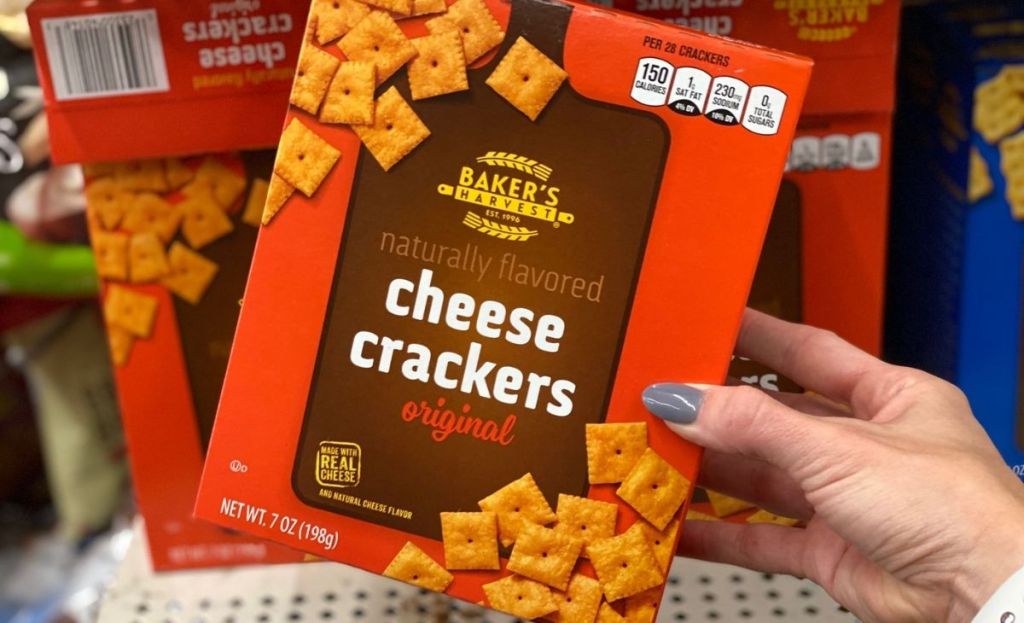 A hand grabbing a box of cheese crackers off a store shelf