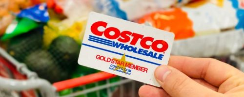 hand holding a Costco membership card in front of groceries