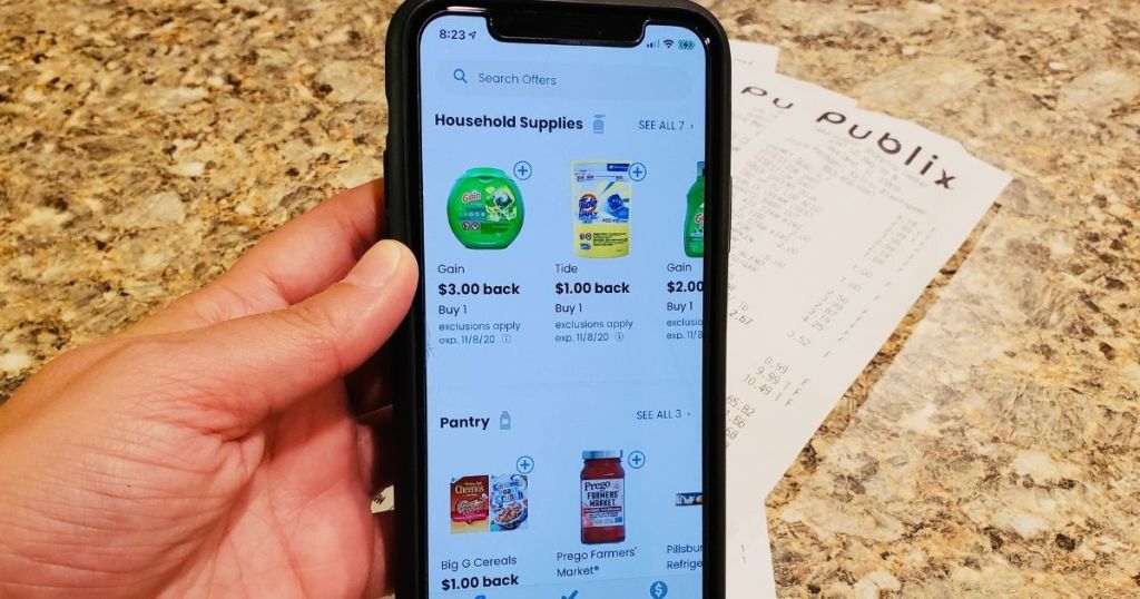 hand holding a phone with the Coupons.com app
