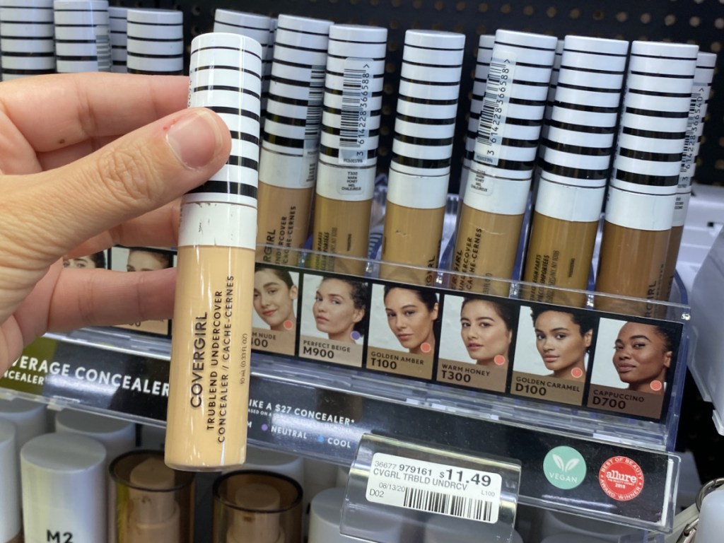 hand holding tube of concealer in store