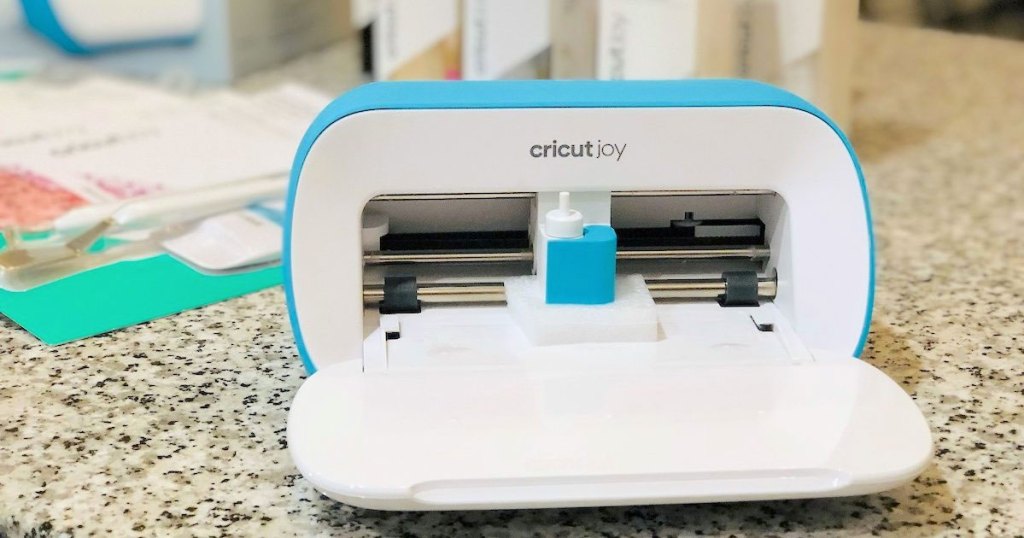 blue and white cricut joy machine on counter in front of crafting supplies