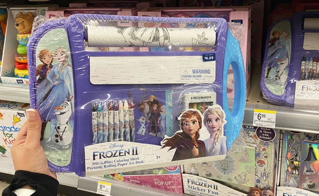 person holding up disney frozen art desk with roll of coloring paper