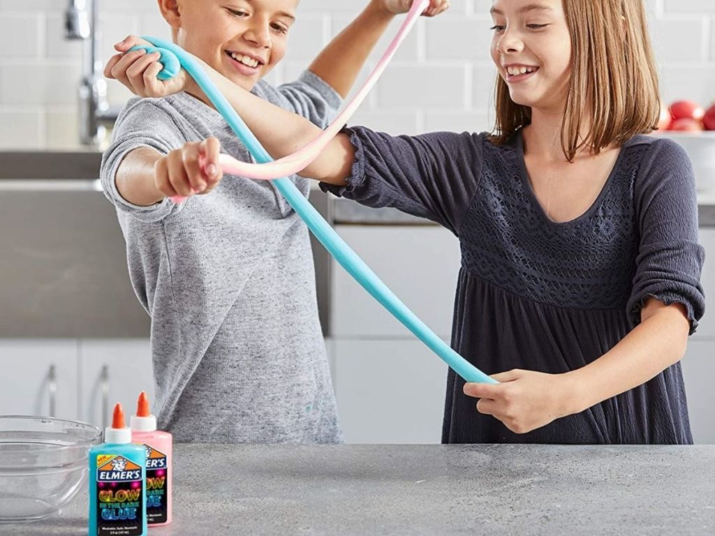 kids playing with glow in the dark slime with Elmer's glue bottles in front of them