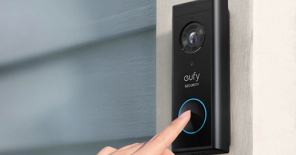finger pressing a button on a Eufy Doorbell mounted on a wall