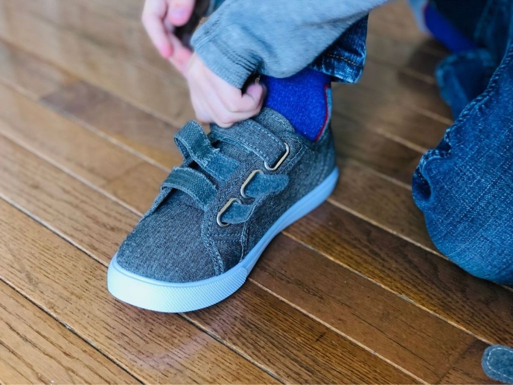 boy putting on canvas sneakers