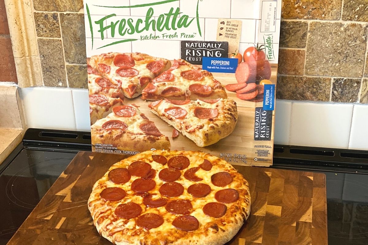 pizza on top of a stove next to the original box 