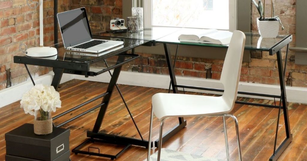 l-shaped desk with glass top and black legs in home office
