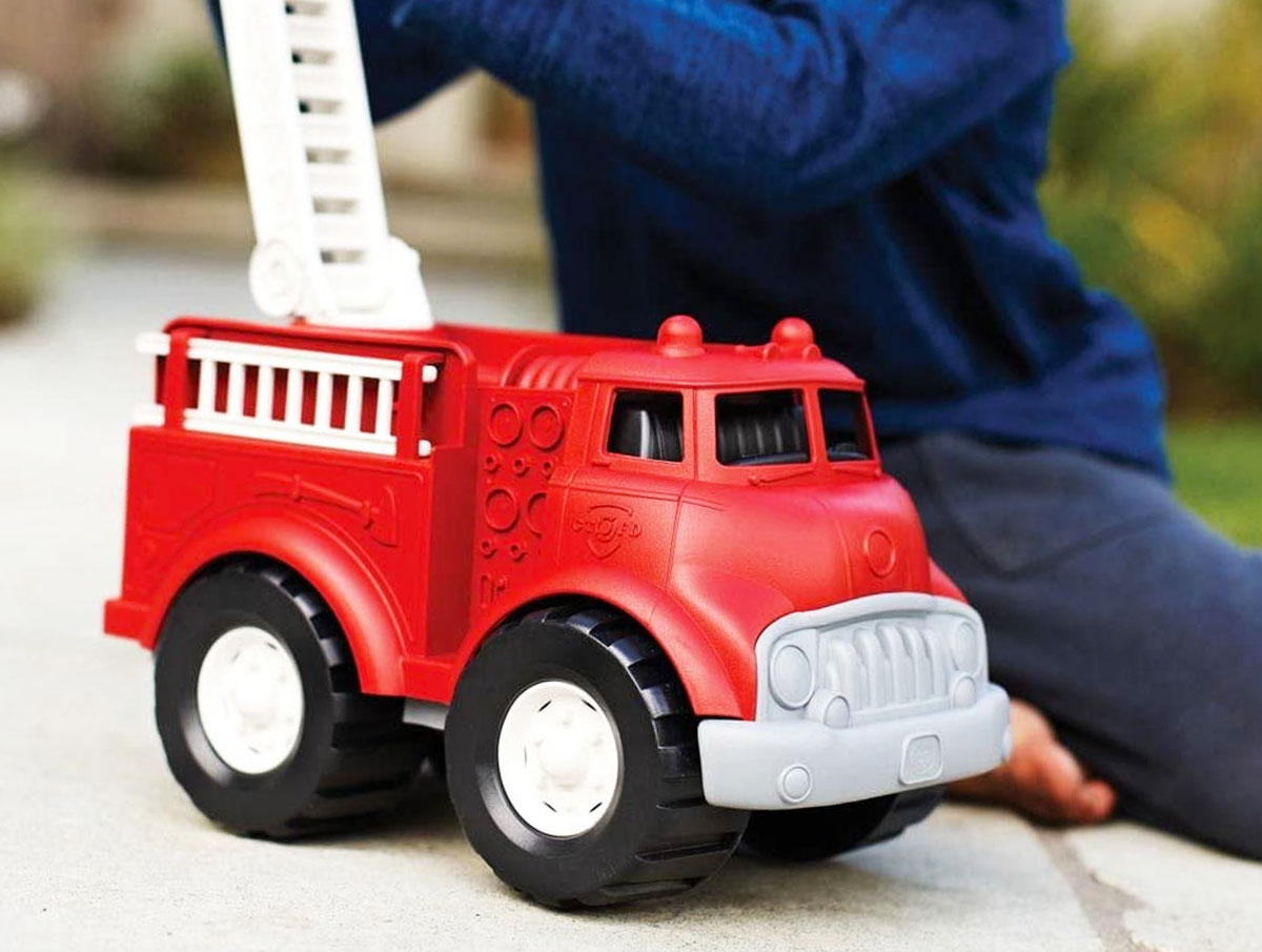 boy playing with a red firetruck toy with moveable ladder