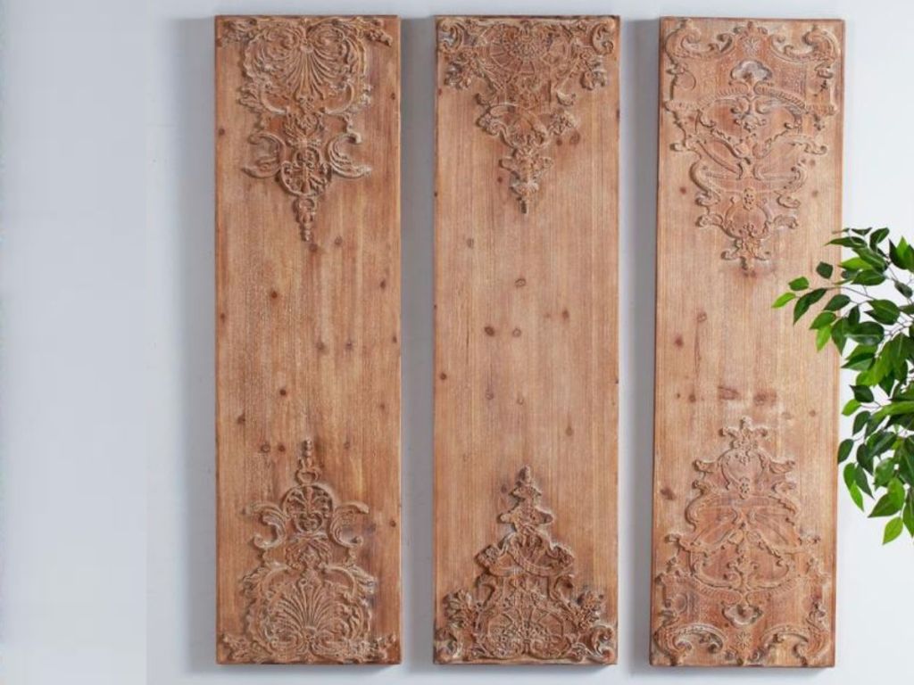 hand-carved wood set on gray wall with plant in corner