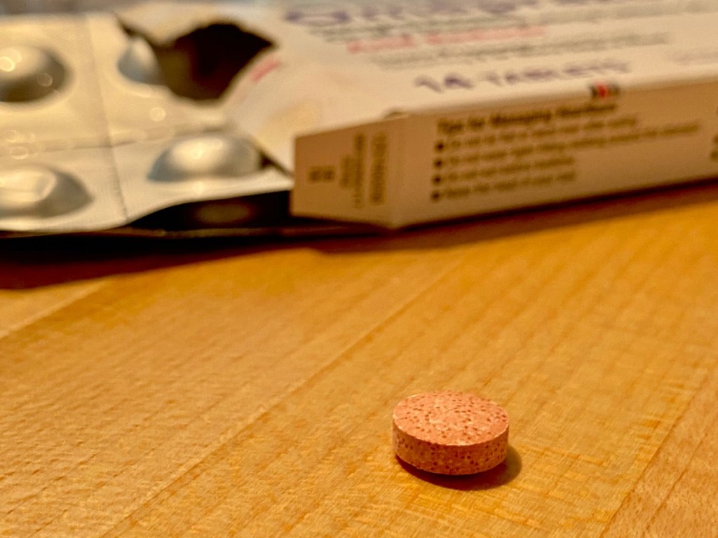 pink Heartburn tablet on wooden counter