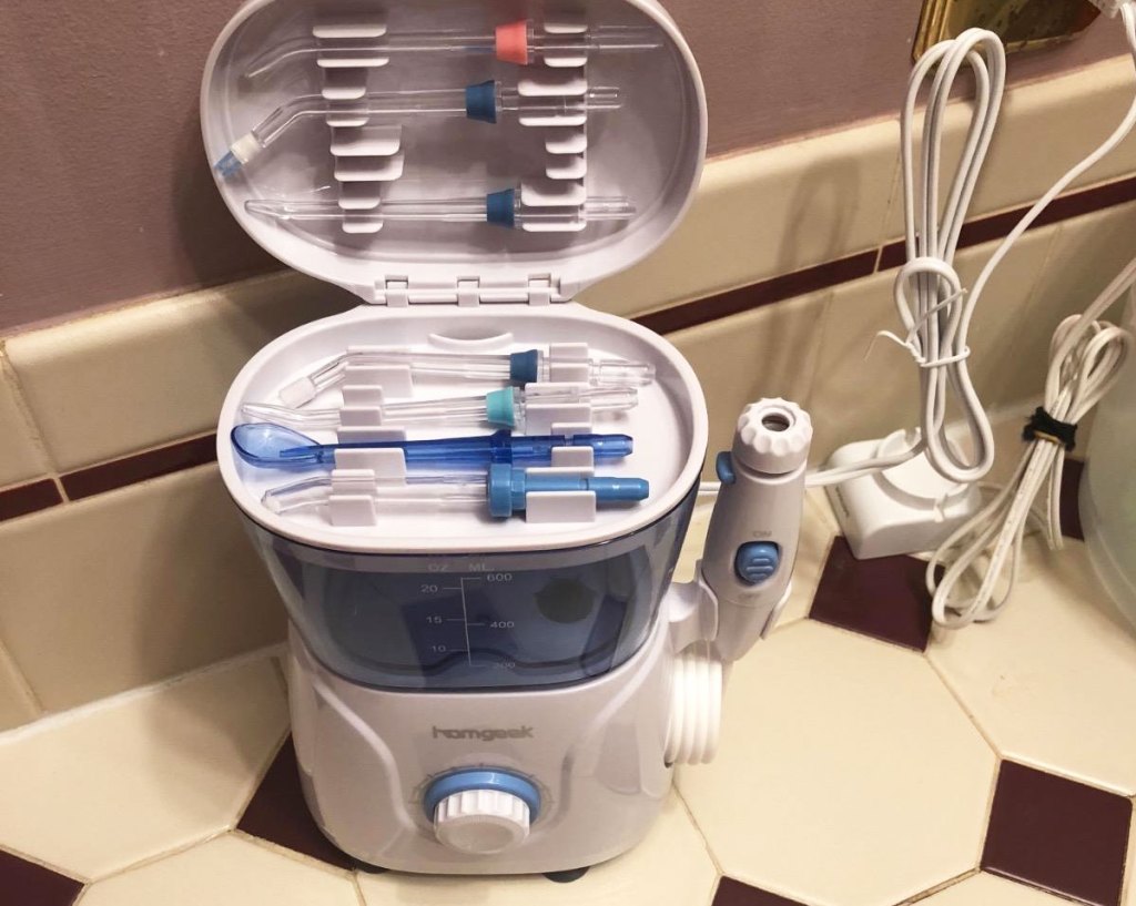 white and blue water flosser on bathroom counter with lid open showing attachments