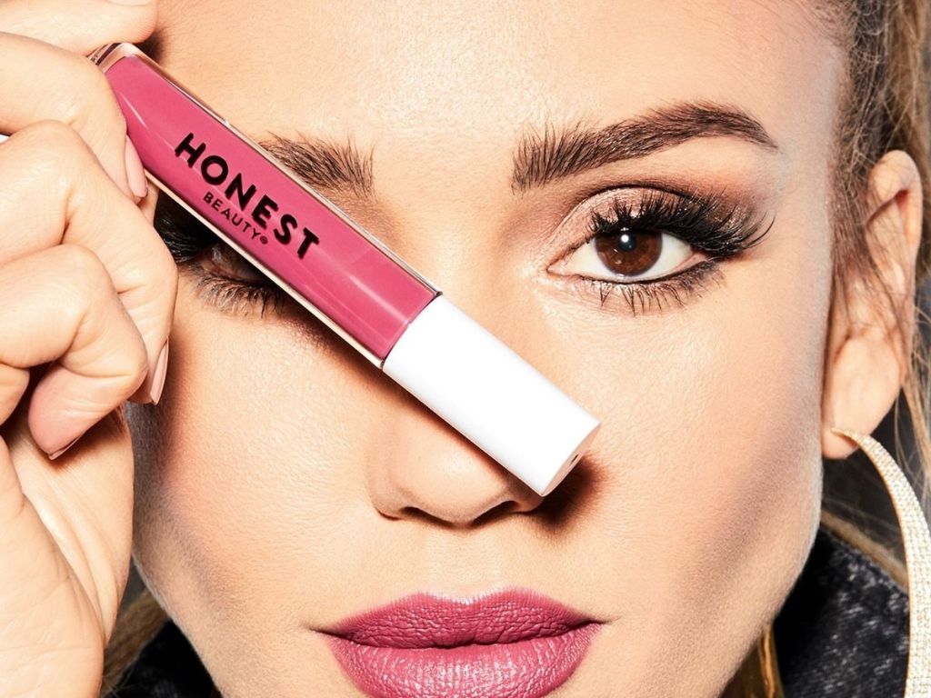 woman holding up Honest Beauty Lip Gloss to her face