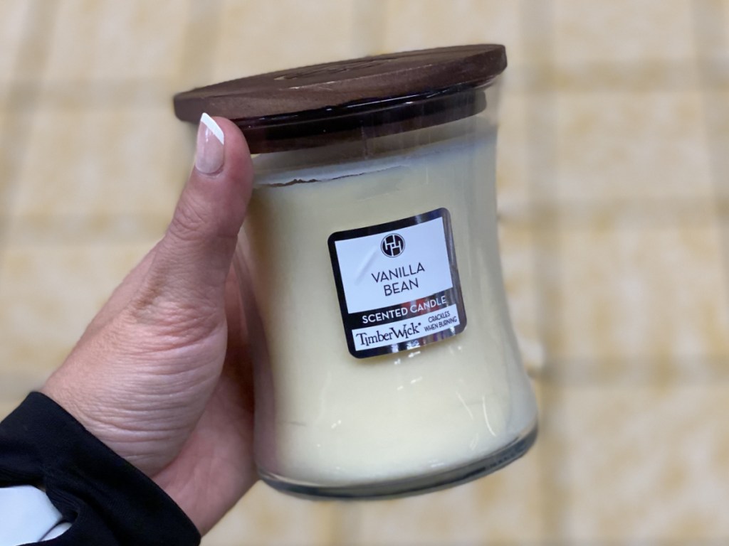 manicured hand holding vanilla bean scented candle