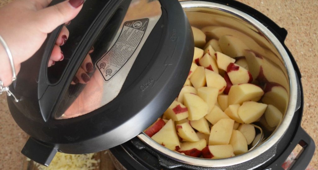 woman putting the lid on an instant pot filled with cut potatos