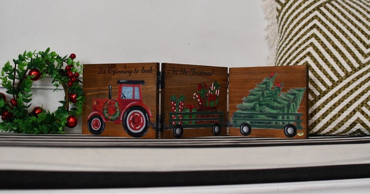 Holiday truck tabletop sign on mantle with holiday wreath next to it