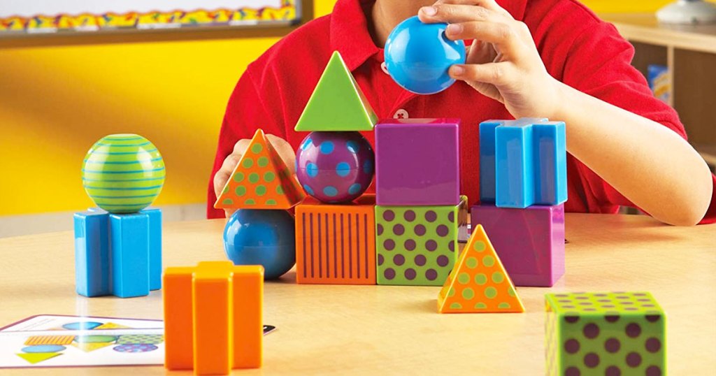 boy in red shirt playing with colorful blocks and shape on wood table