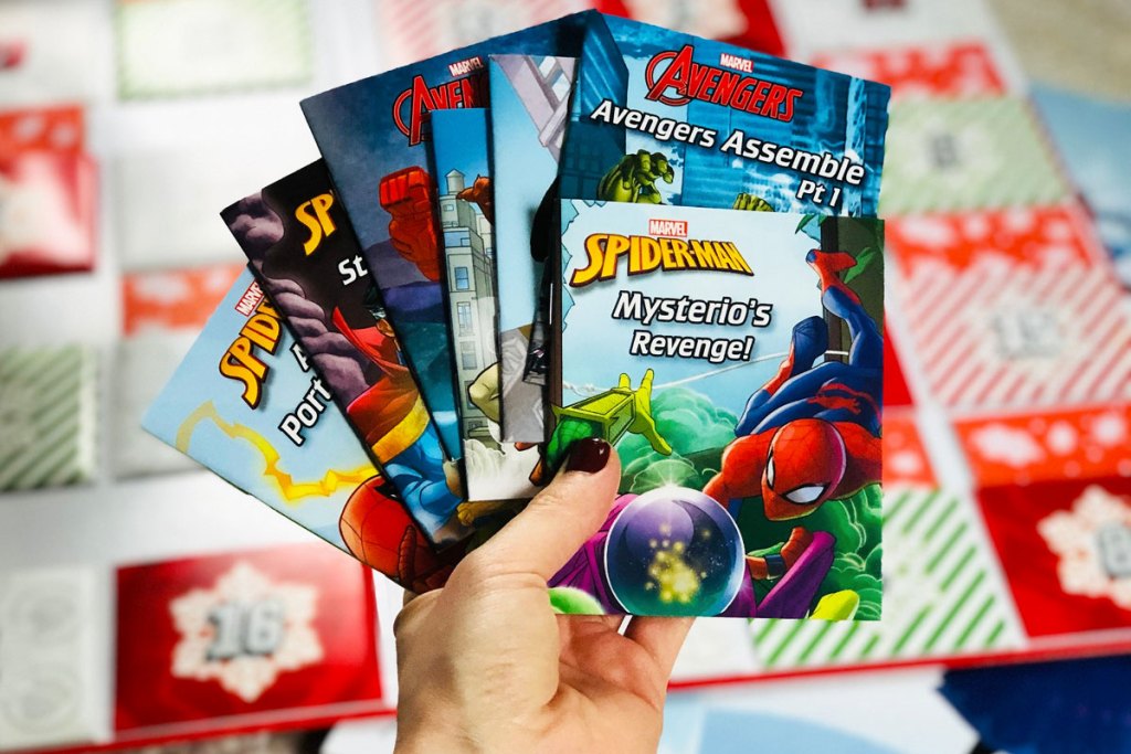 person holding up a variety of books that come inside the marvel storybook advent calendar