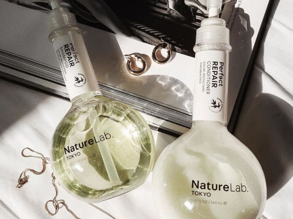two bottles of nature lab tokyo shampoo and conditioner with jewelry near by