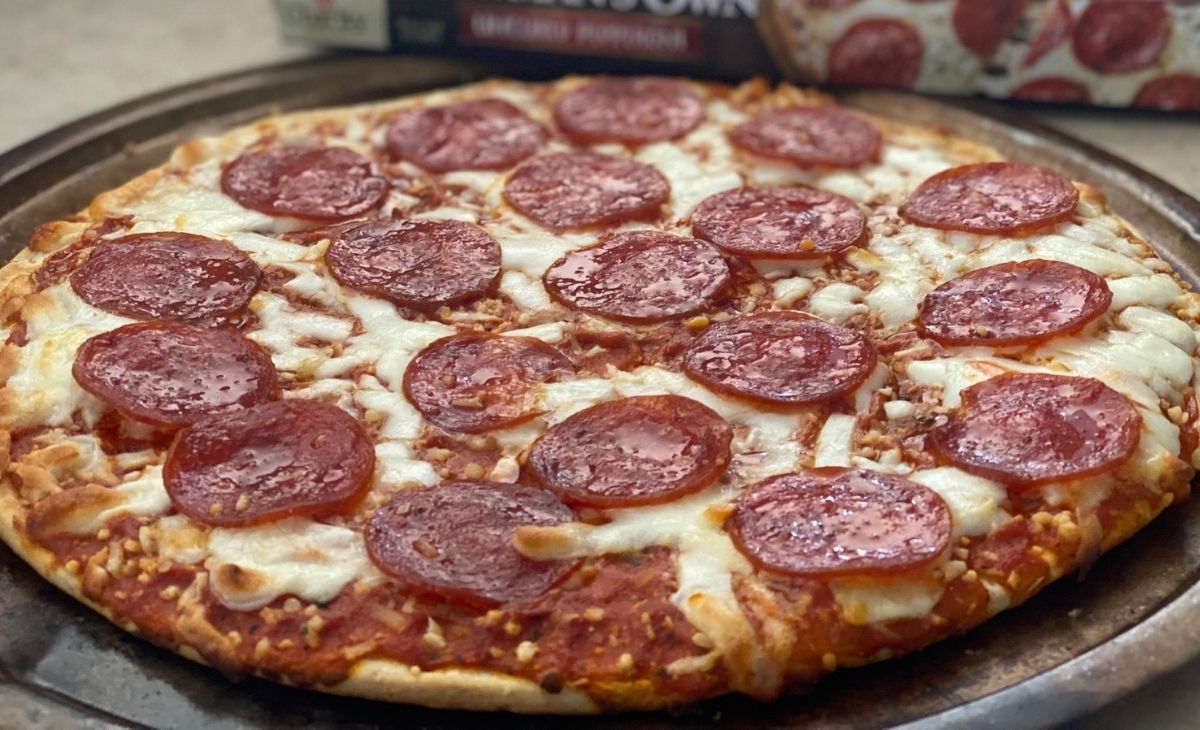 A newman's own pepperoni pizza on a pizza pan 
