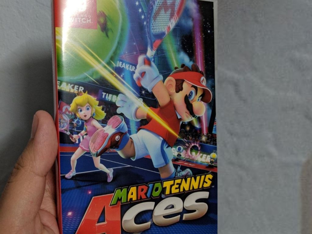 hand holding Mario Tennis Aces game